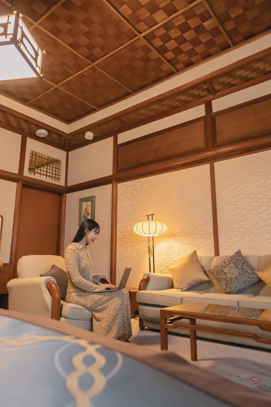 Woman on a computer on a sofa in a guest room