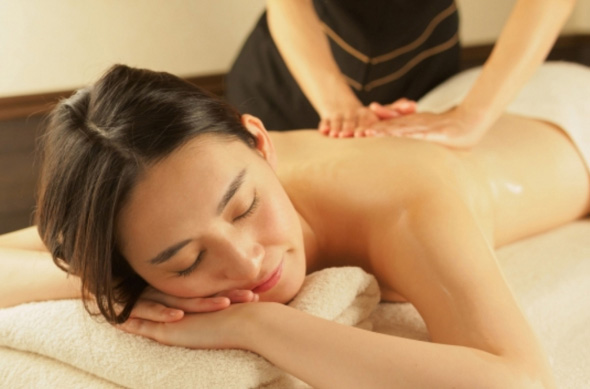 A woman receiving a massage at a spa. She looks relaxed as she surrenders herself to the comfortable treatment