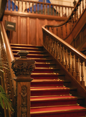 Picture of a wooden staircase with red carpet. It gives an elegant and calm impression